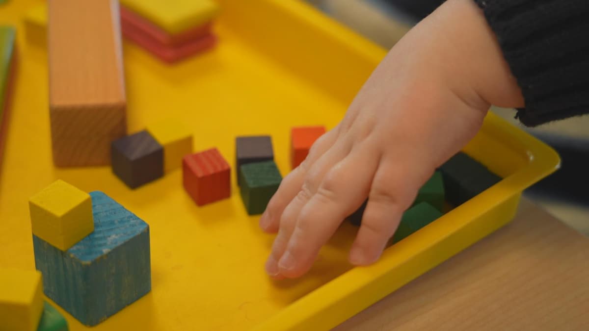 La main d'un enfant attrappe des jouets en bois colorés. 