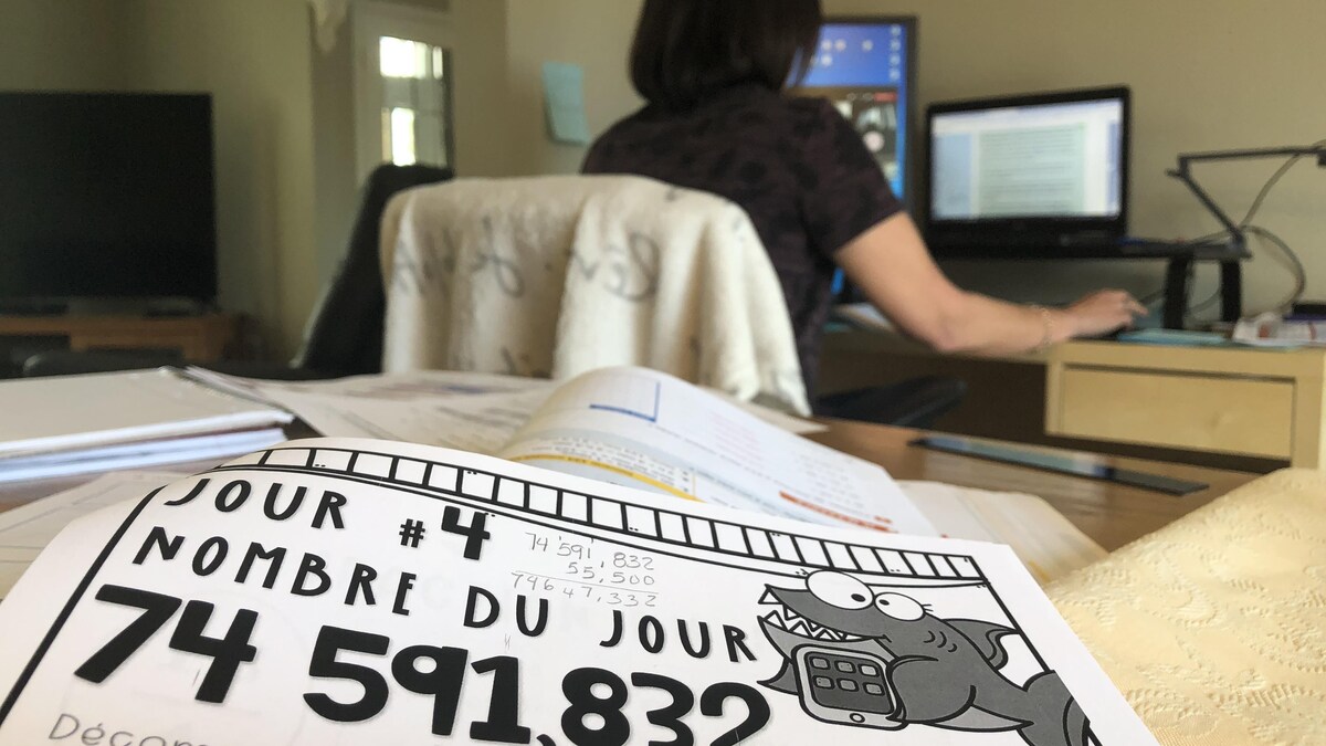 Une enseignante donne un cours, devant son écran d'ordinateur.