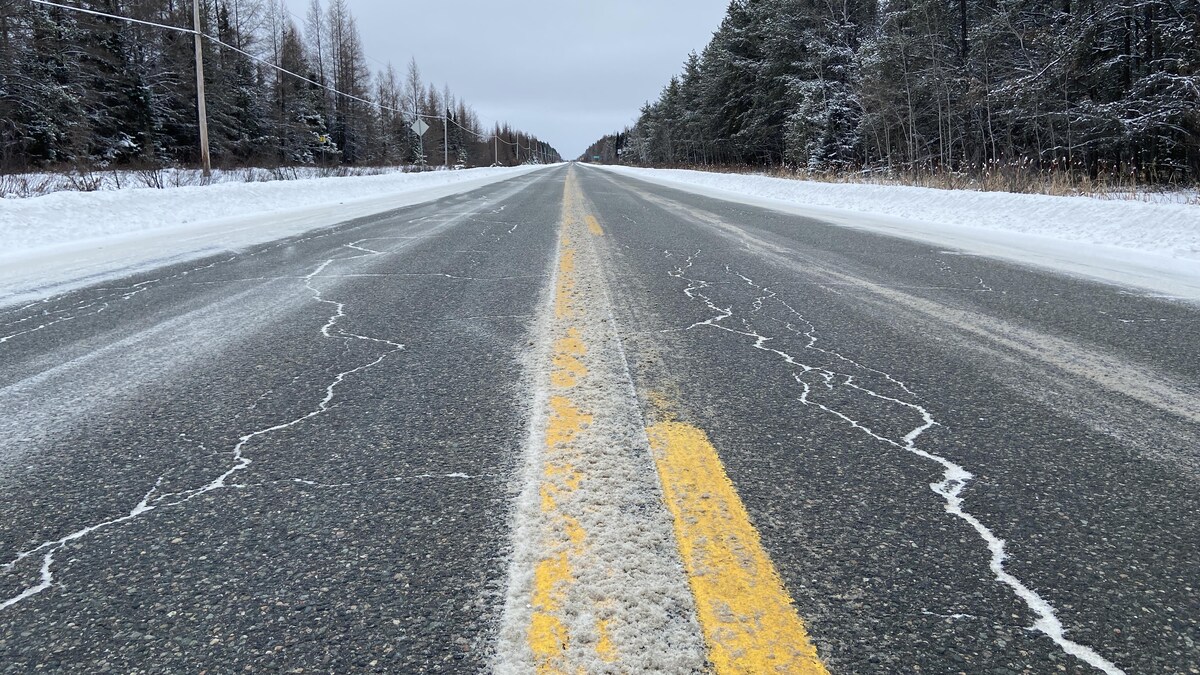 Gros plan d'une route partiellement enneigée.