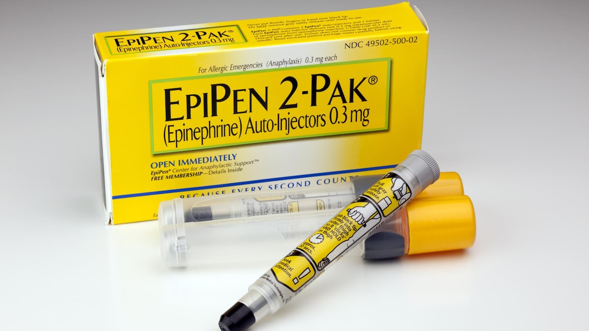 Un auto-injecteur d'épinéphrine de type EpiPen en avant-plan avec la boîte derrière