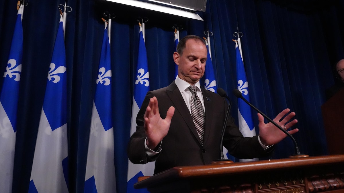 Un homme derrière un lutrin en conférence de presse.