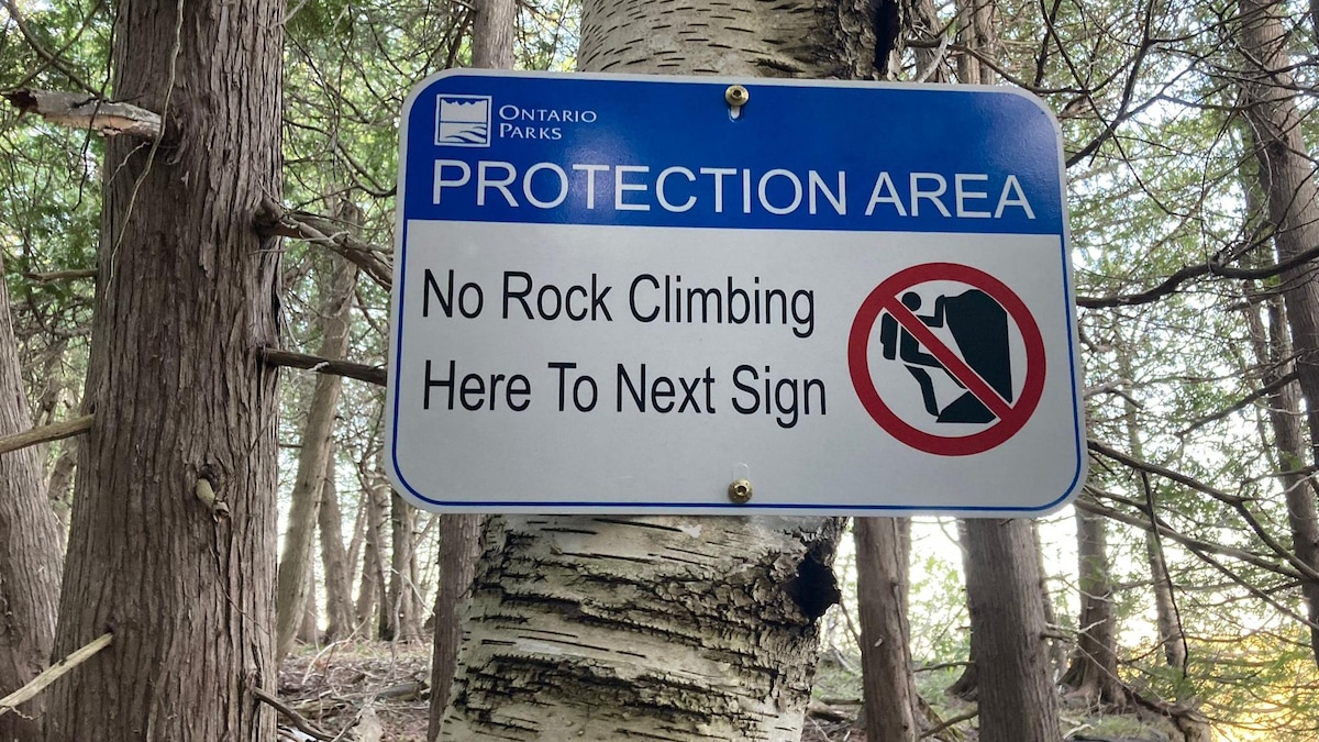 Une pancarte où on peut lire « aire protégée » et « pas d'escalade ».