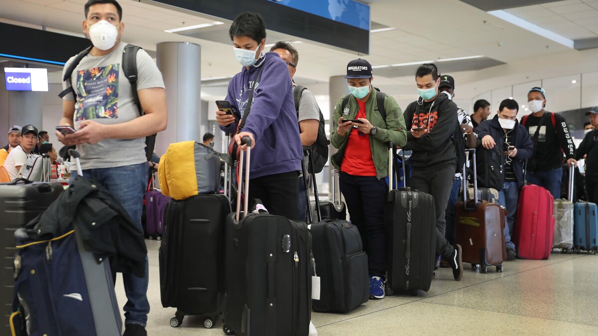 Des voyageurs en attente dans un corridor de l'aéroport international de Miami, en Floride.