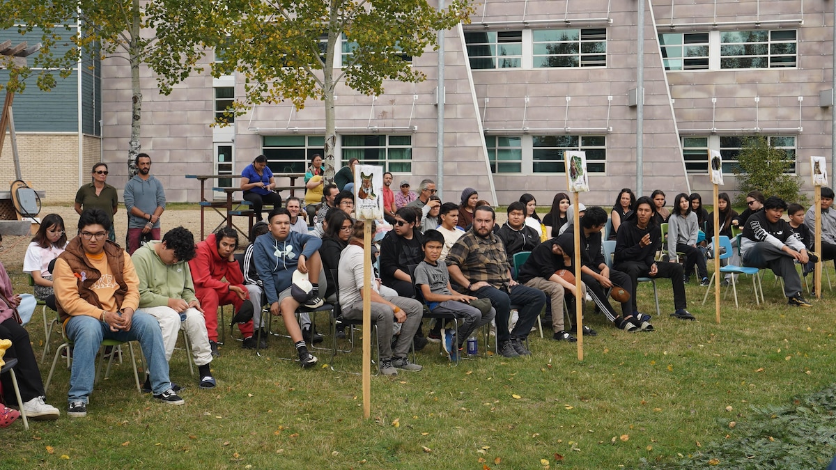 Plusieurs étudiants assis sur des chaises à l'extérieur.