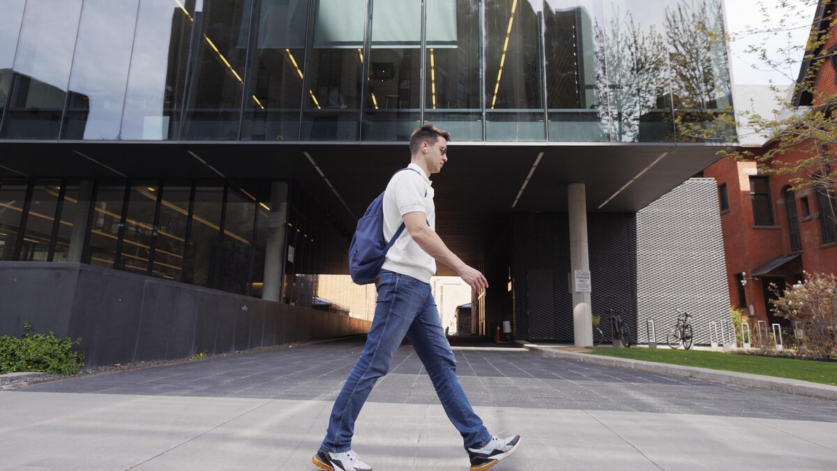 Un jeune homme marche devant la bibliothèque Robart en mai.