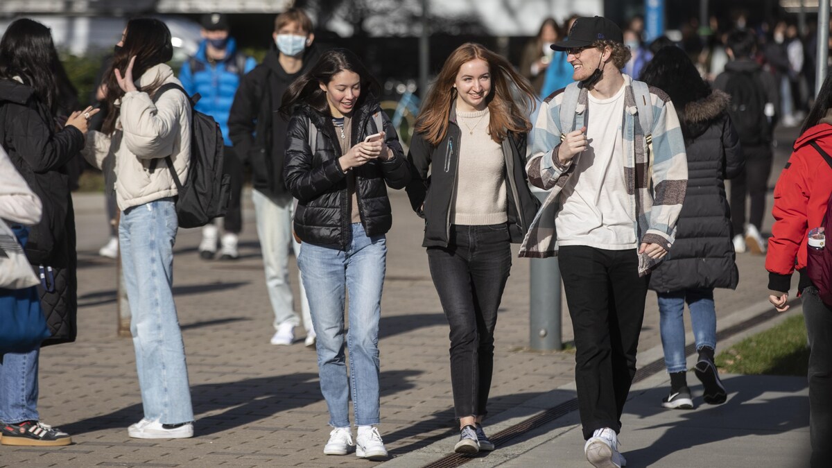 Des étudiants souriants déambulent sur un campus universitaire.