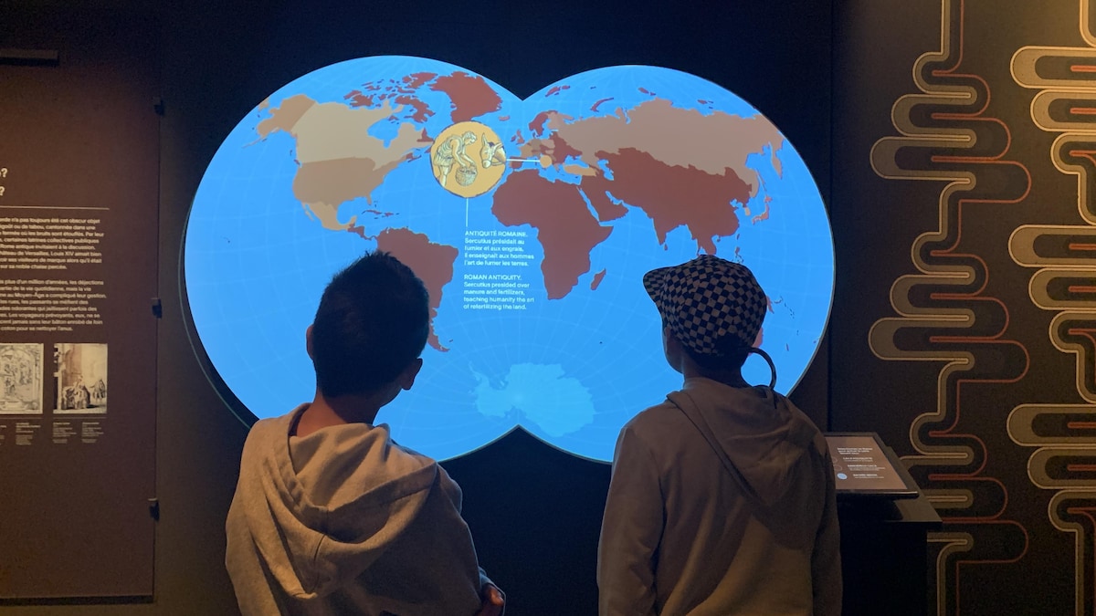 Deux garcons observent une carte du monde animée. 