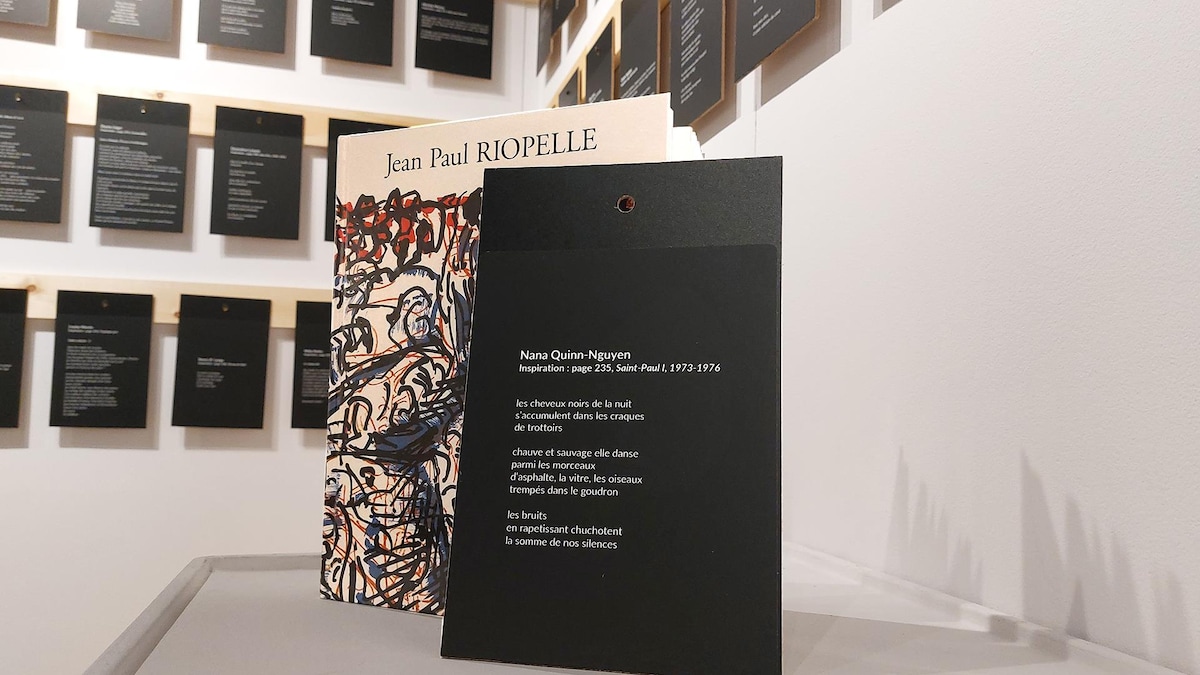 Un poème inscrit sur une carte amovible repose le long d'un livre qui rassemble des œuvres de Riopelle.