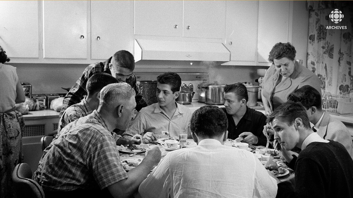 Une famille nombreuse mange autour d'une table ronde dans une cuisine. 