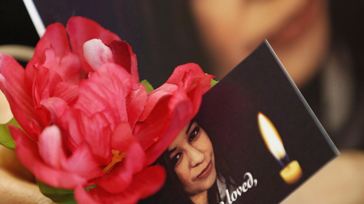 Une femme tient des fleurs et une photo représentant Christine Wood, une jeune femme autochtone de Winnipeg portée disparue au printemps 2016. Les restes de Mme Wood ont été retrouvés près d'un an plus tard, dans un champ de la région.