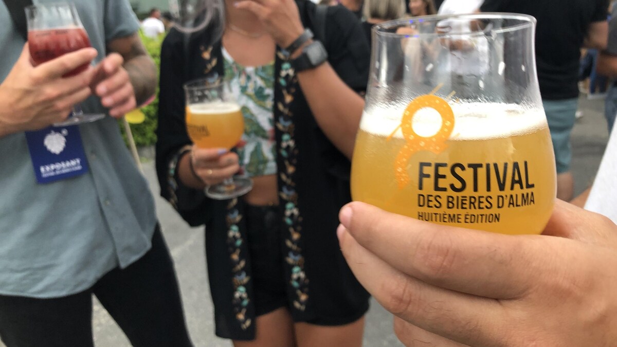 Un verre de bière devant des gens à un festival.
