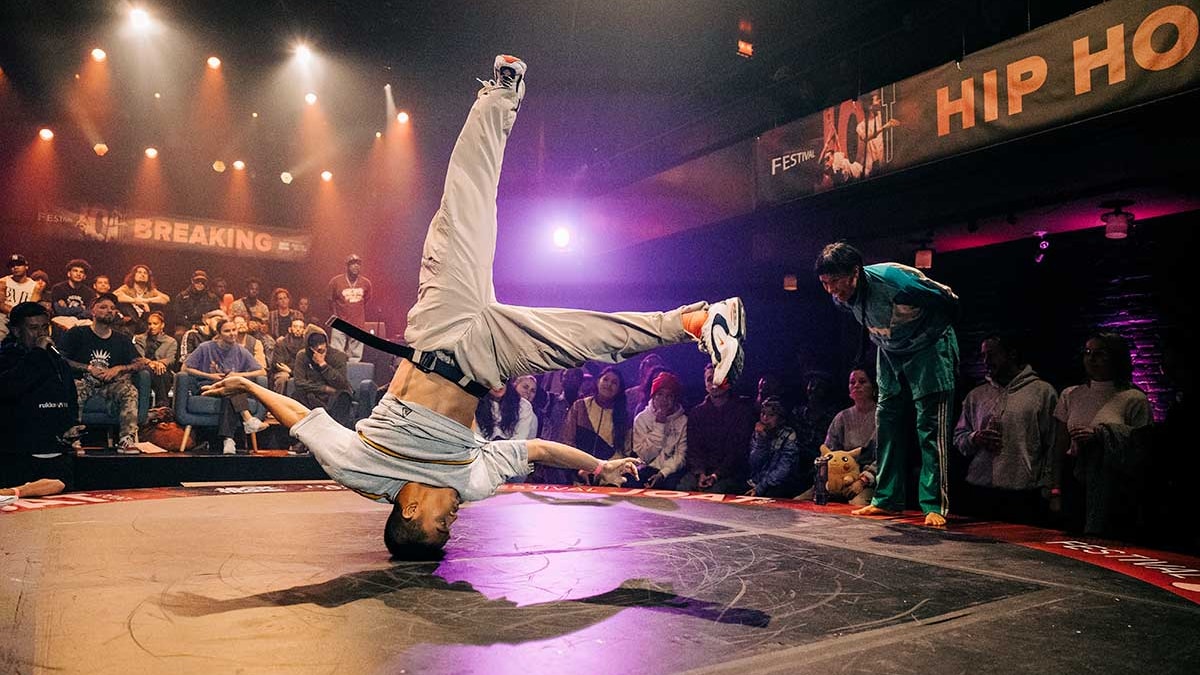 On voit un danseur tournant sur sa tête durant un affrontement hip-hop.