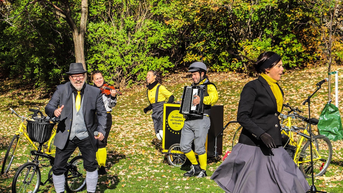 Chanteurs et chanteuses habillés en jaune et noir avec instruments dans un parc. 