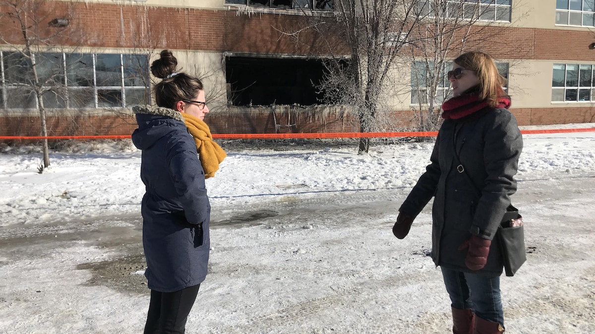 Deux femmes se font face devant un immeuble touché par un incendie.