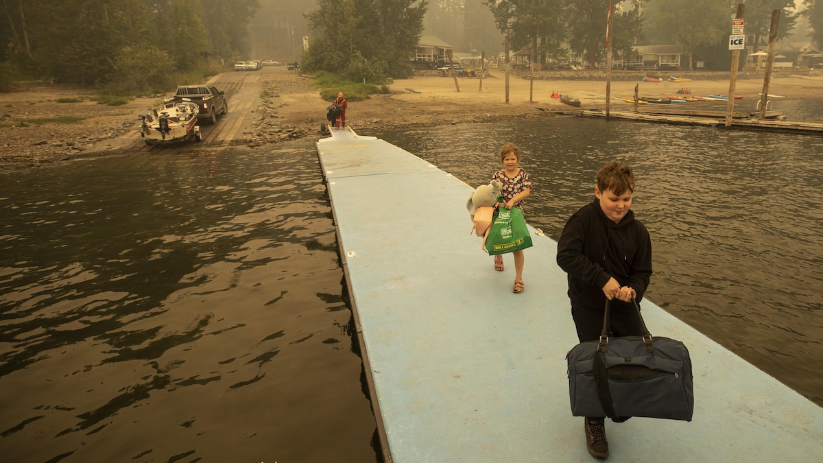 Deux enfants montent sur un ponton pour évacuer leur communauté en bateau. 