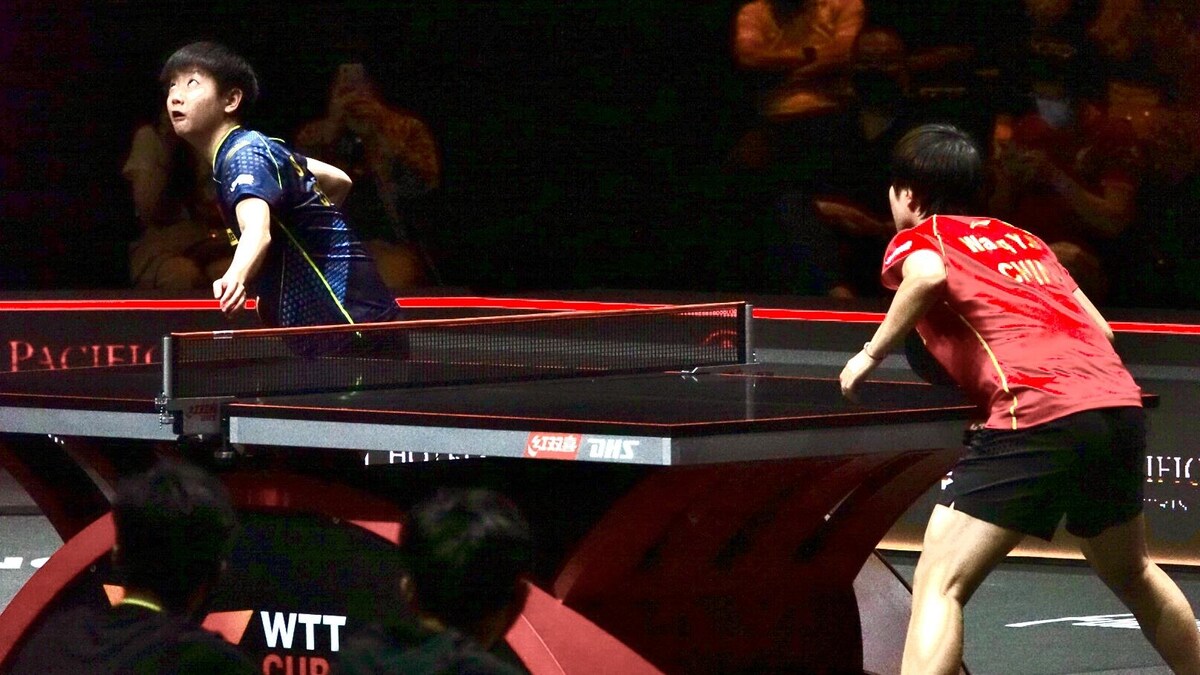Deux personnes jouent au ping-pong dans une salle bondée.
