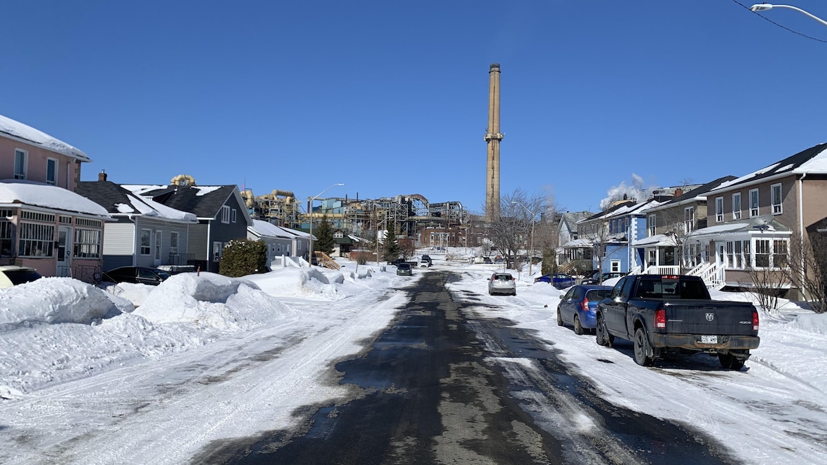 Des maisons et des véhicules stationnés près de la Fonderie Horne et une cheminée de l'entreprise.