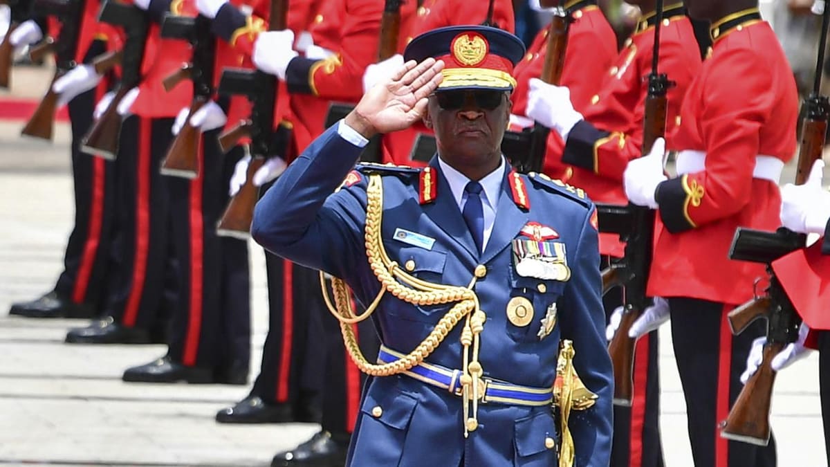 Le général Francis Omondi Ogolla fait un salut, une rangée de ses militaires se trouvent à sa gauche derrière lui.