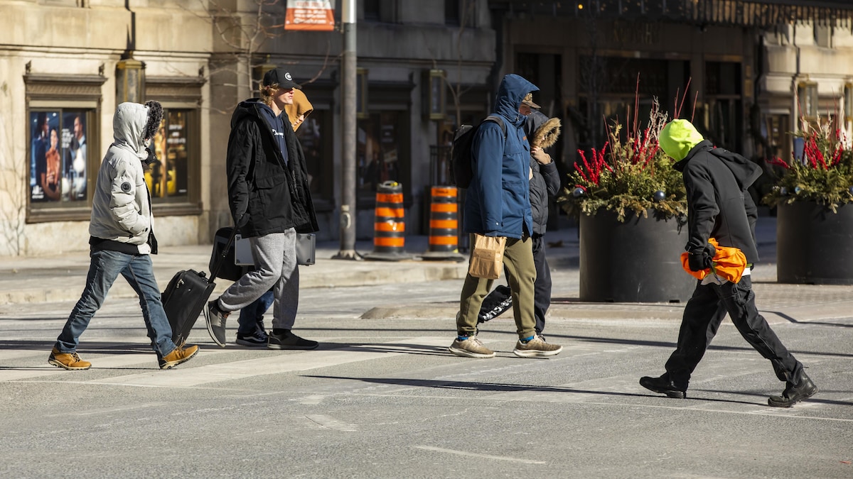 Des gens portant des manteaux d'hiver marchent sur la rue Front à Toronto.