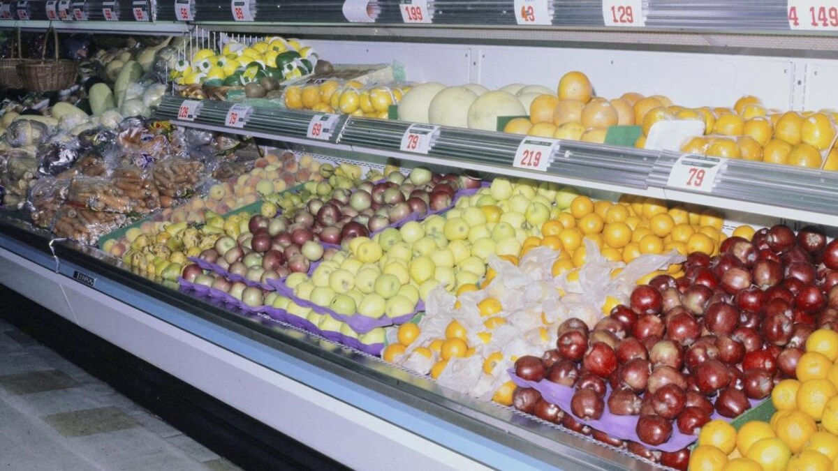 Comptoir de fruits d'une épicerie majoritairement composé de pommes et d'agrumes.