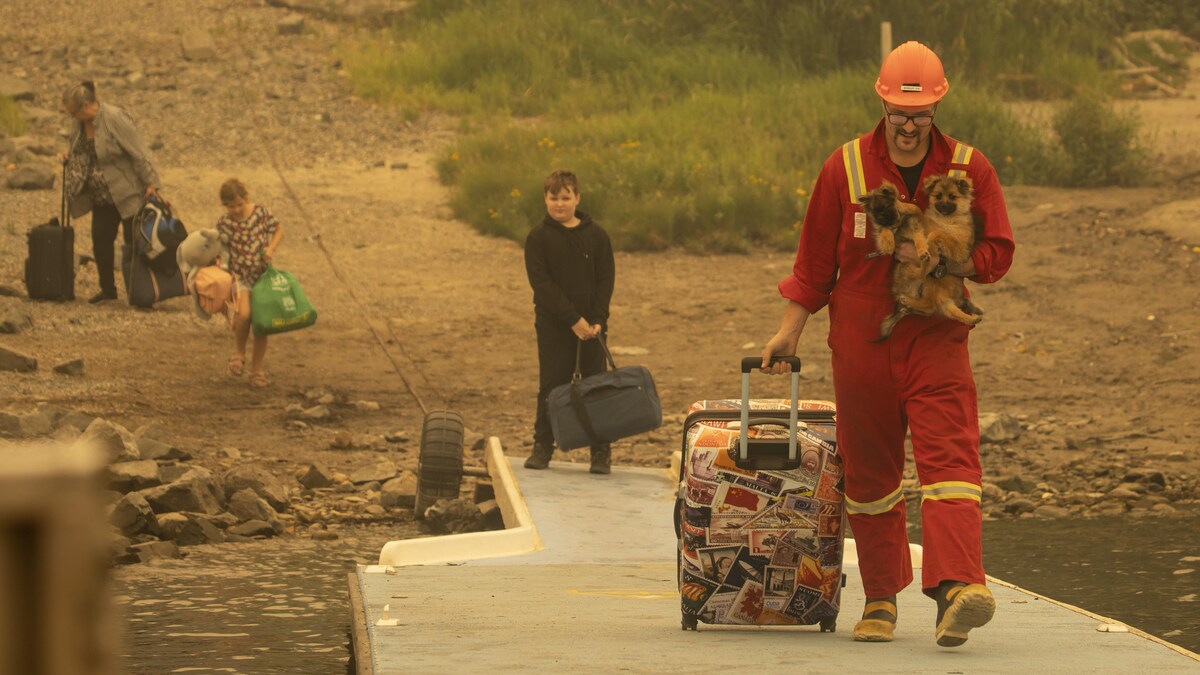 Un homme accompagné de ses enfants transportent des bagages avant d'évacuer. 