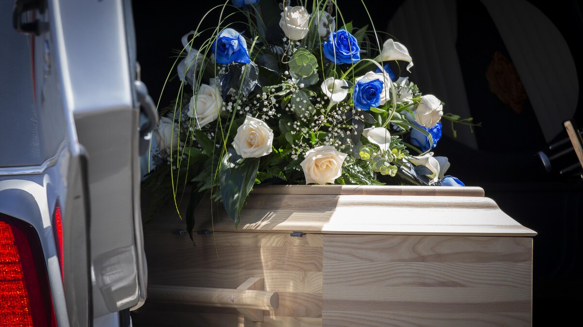 Le cercueil de la petite fille avec une gerbe de fleurs sur le dessus. 