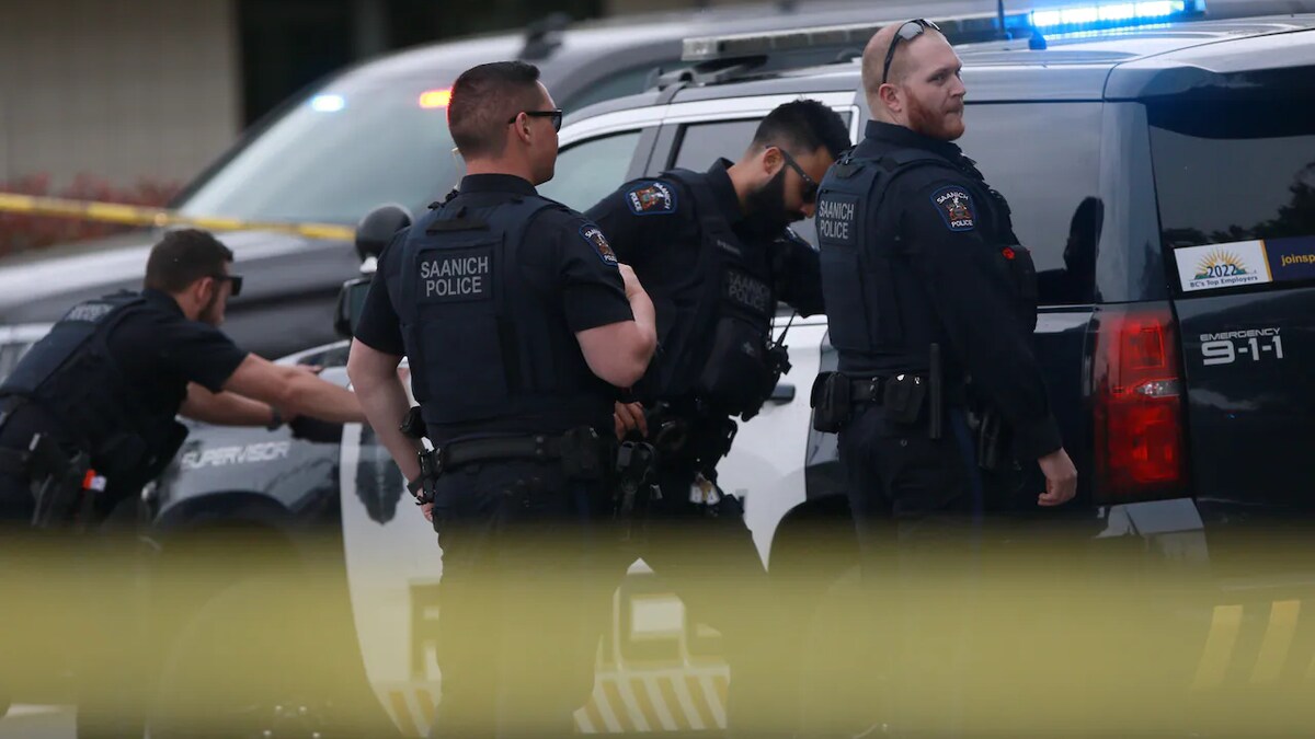Quatre policiers près d'une voiture de police, le 28 juin 2022, à Saanich, sur l'île de Vancouver