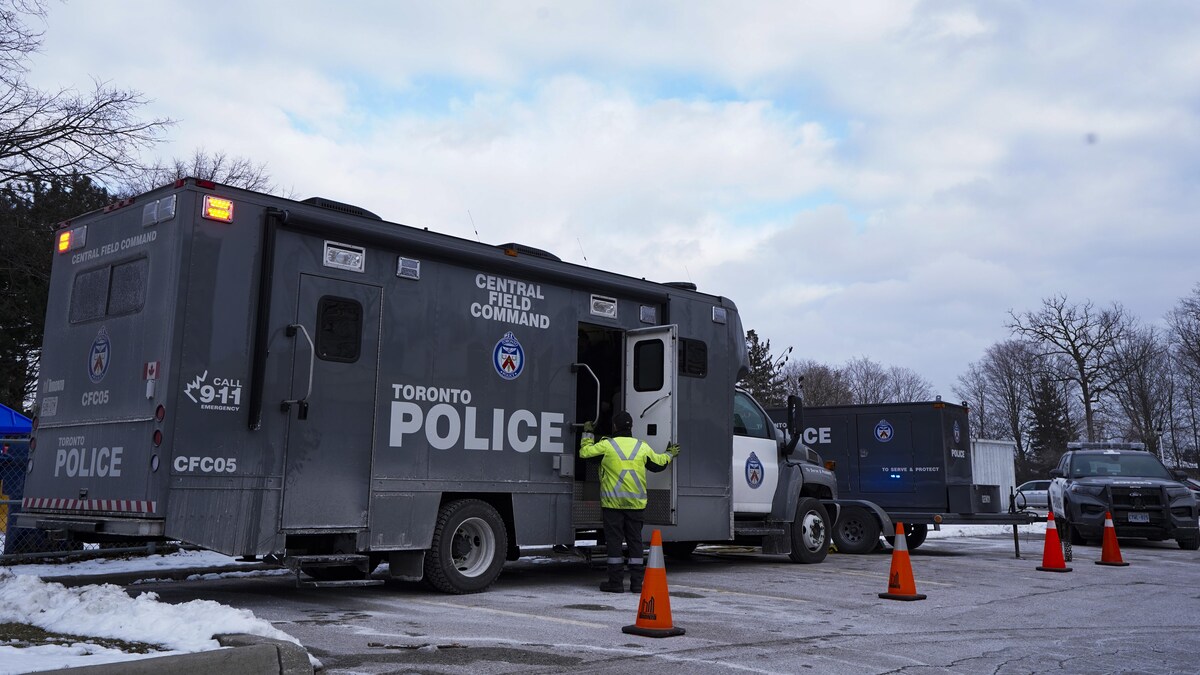 Un homme entre dans un camion de la police de Toronto stationné avec d'autres véhicules sur l'avenue Driftwood où deux fusillades ont eu lieu. 