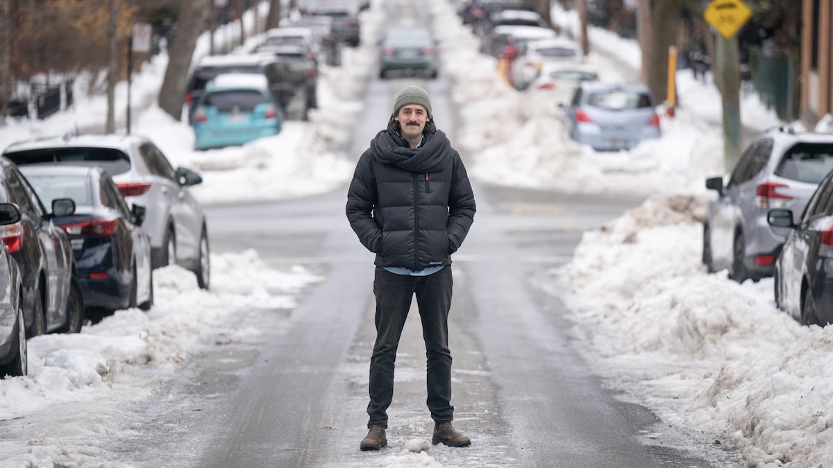 Un jeune homme se tient debout au milieu d'une rue enneigée à Montréal.