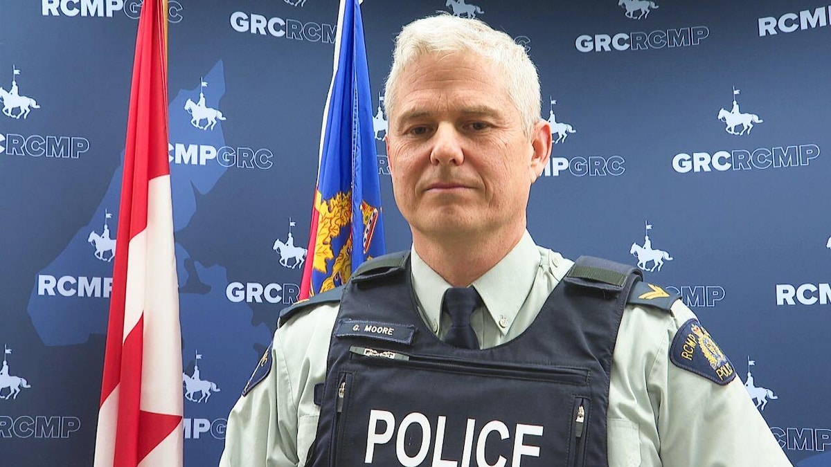 Gavin Moore, caporal à la Gendarmerie royale du Canada de l'Î.-P.-É. et chargé des relations avec les médias, devant un mur avec le logo de la GRC.