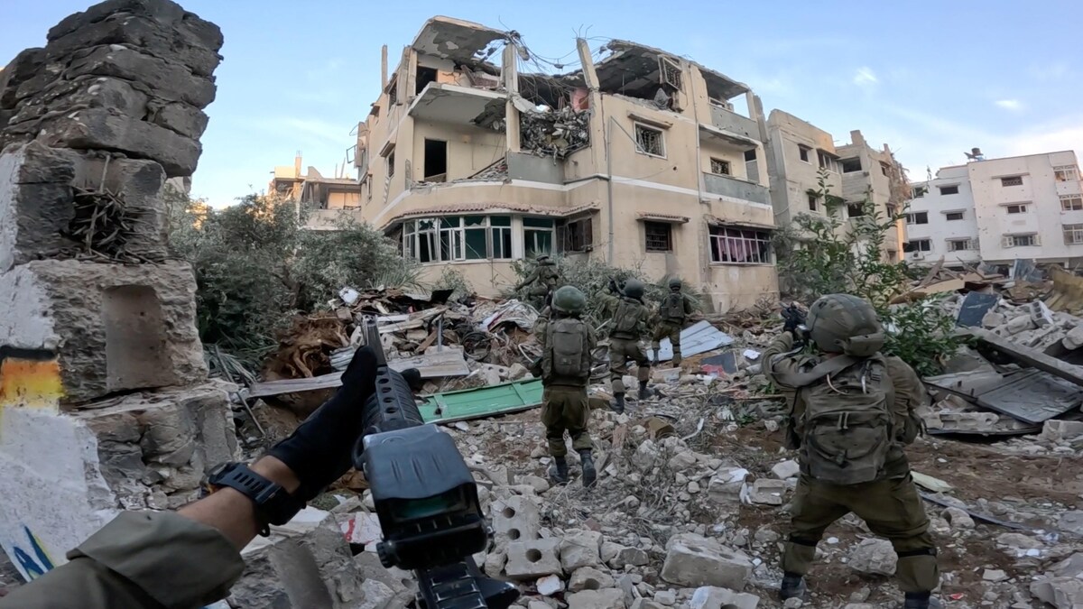 Des soldats armés avancent dans les décombres d'une ville. 