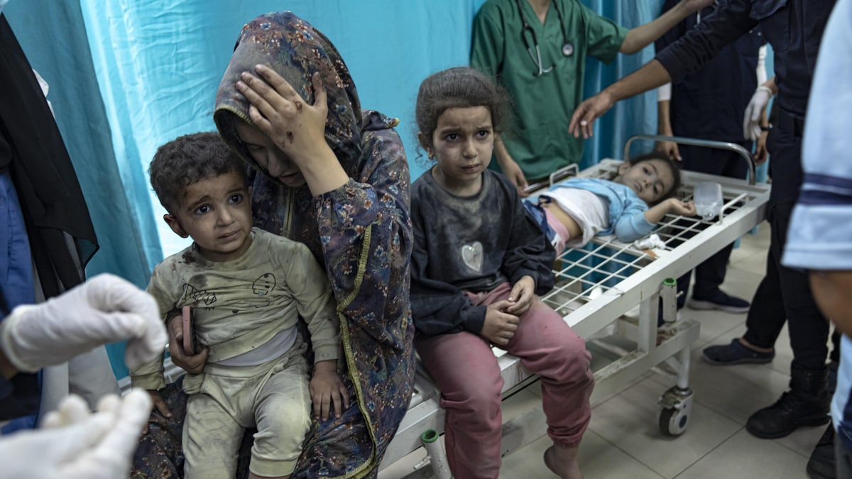 Une femme blessée à la tête est assise sur une civière en compagnie d'enfants.