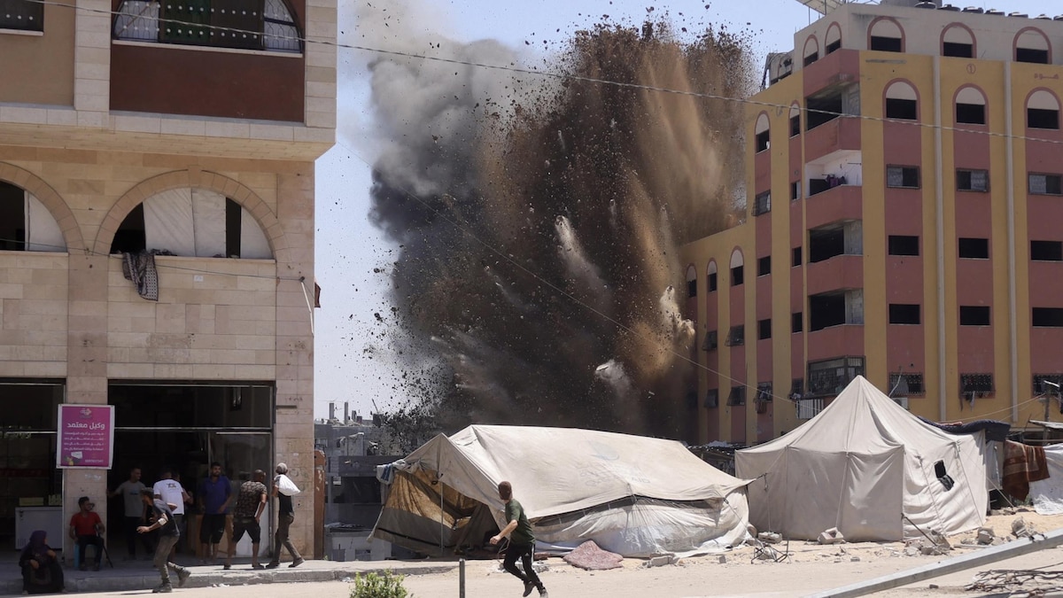 Des Palestiniens se précipitent pour se mettre à l'abri alors que de la fumée s'élève après une frappe israélienne sur un bâtiment à Jabalia, dans le nord de la bande de Gaza, le 20 août 2025.