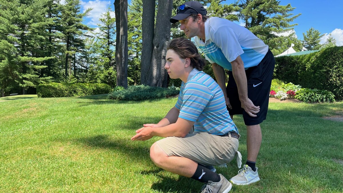 Un adolescent et un homme sont en position accroupie sur un terrain de golf.