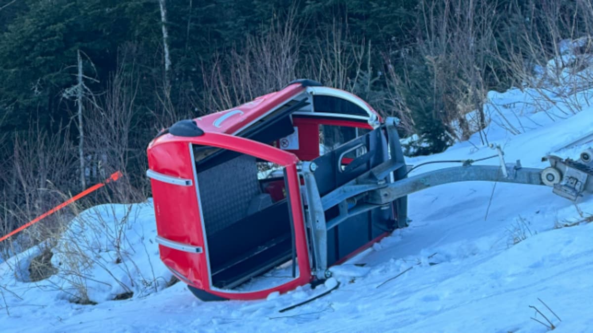 Une télécabine, couchée dans la neige sur le sol.