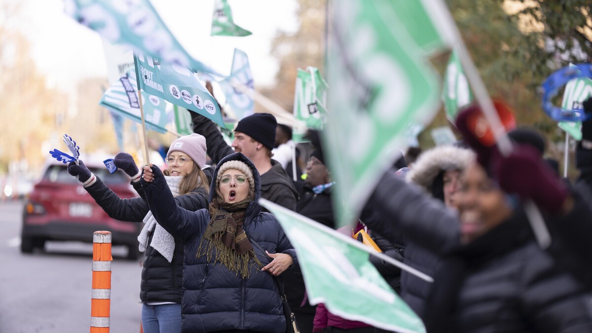 Des grévistes brandissent des drapeaux en bordure d'une rue.