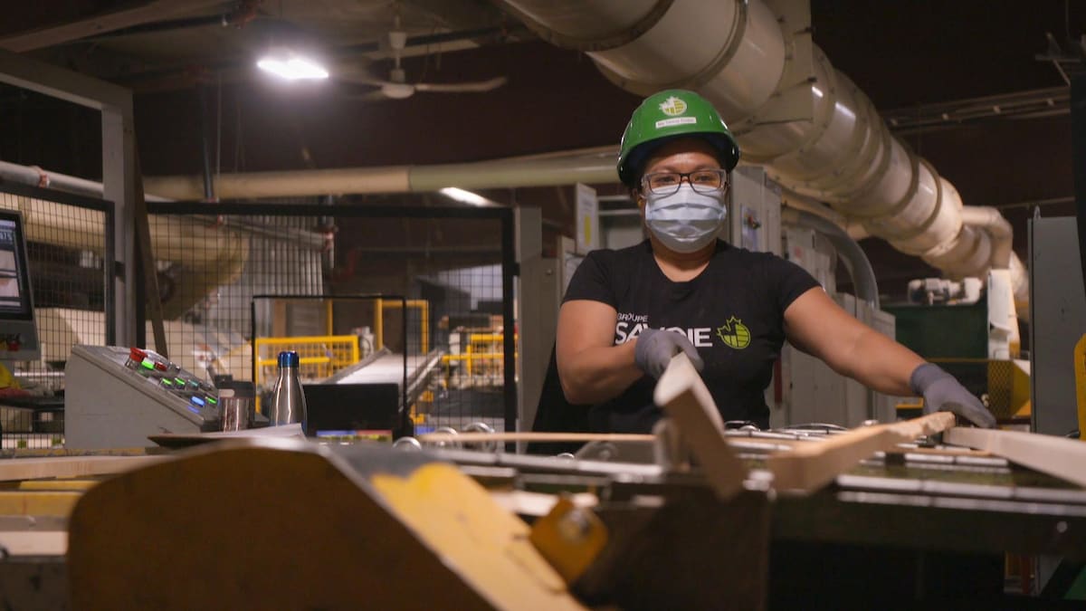 Une femme d'origine philippine manipule des pièces de bois sur une machine dans l'usine.