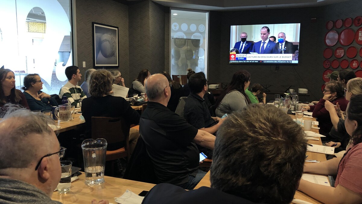 Des personnes sont assises dans une salle et écoutent le ministre des Finances.