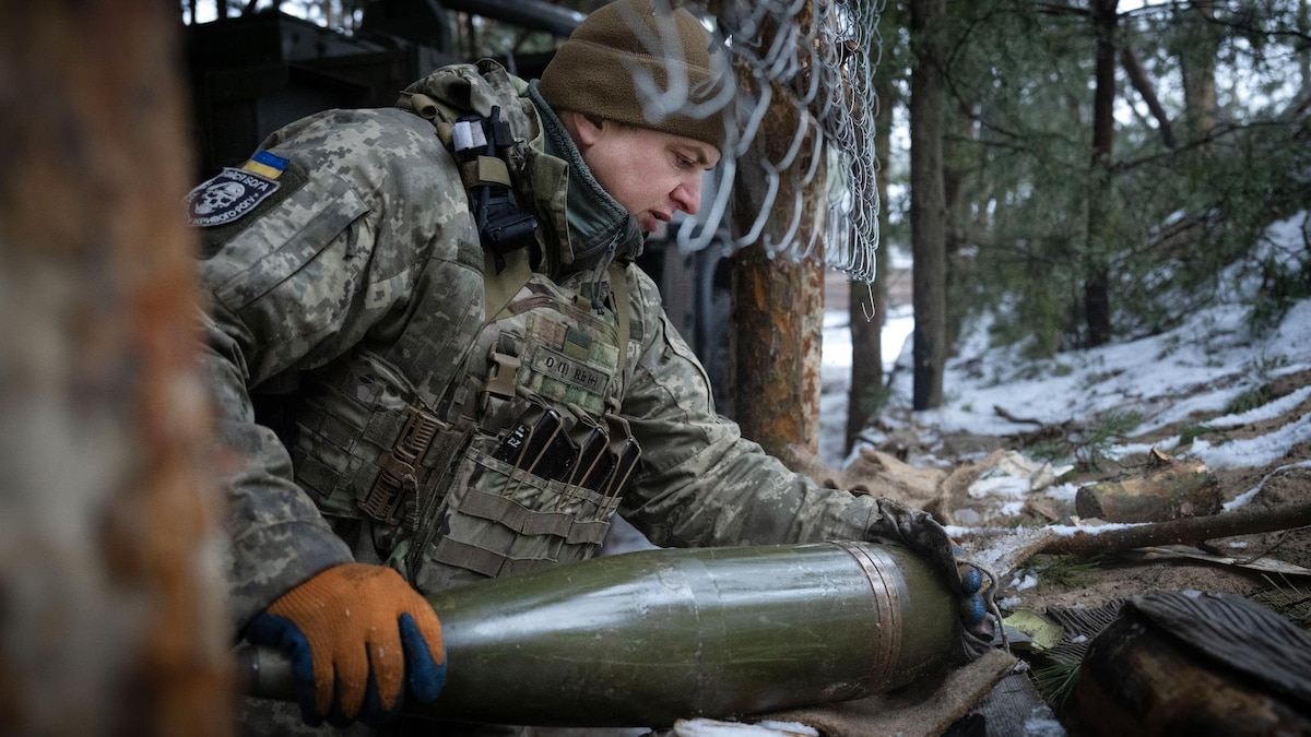 Un militaire place un obus dans un canon. 