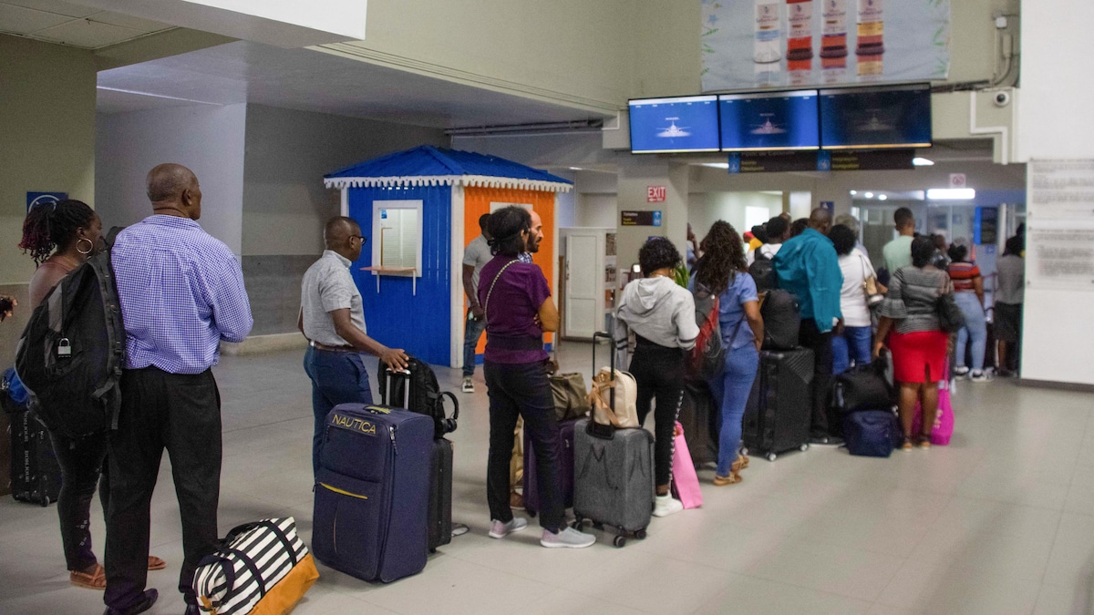 Des voyageurs font la file dans un hall d'aéroport.