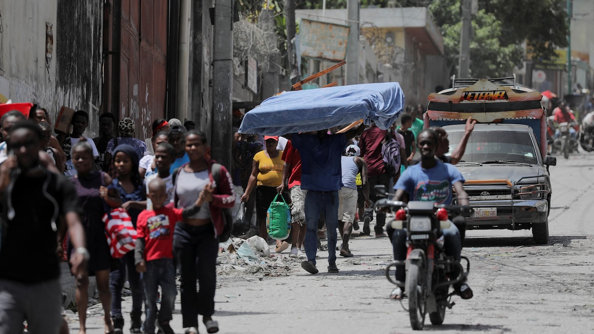 Un homme porte un matelas alors que lui et d'autres fuient leur quartier de Carrefour-Feuilles après que des gangs en eurent pris le contrôle, à Port-au-Prince, le 15 août 2023.
