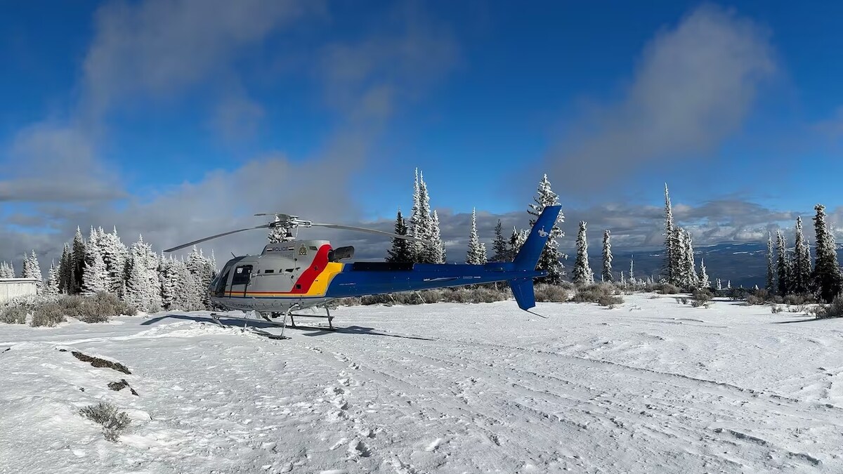 L'hélicoptère aux couleurs de la GRC est dans un champ enneigé, sous un ciel bleu.
