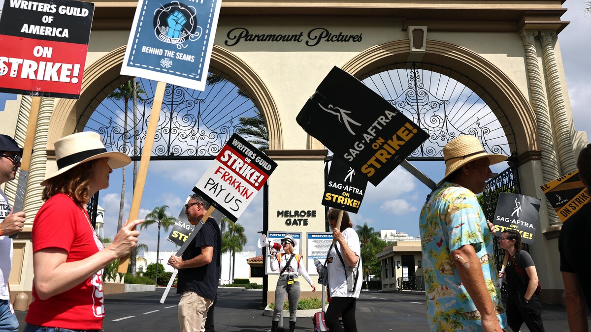 Des manifestants avec des pancartes devant un édifice.