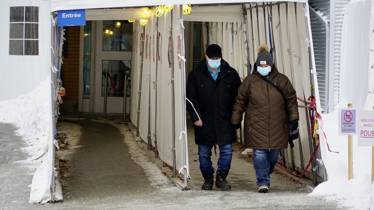           Deux personnes marchent dans l'entrée avec un masque.                     