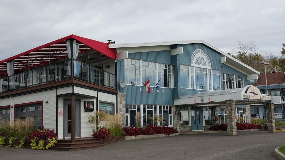 La façade de l'Hostellerie Baie Bleue et du Pub Saint-Joseph, qui comporte une terrasse au deuxième étage.