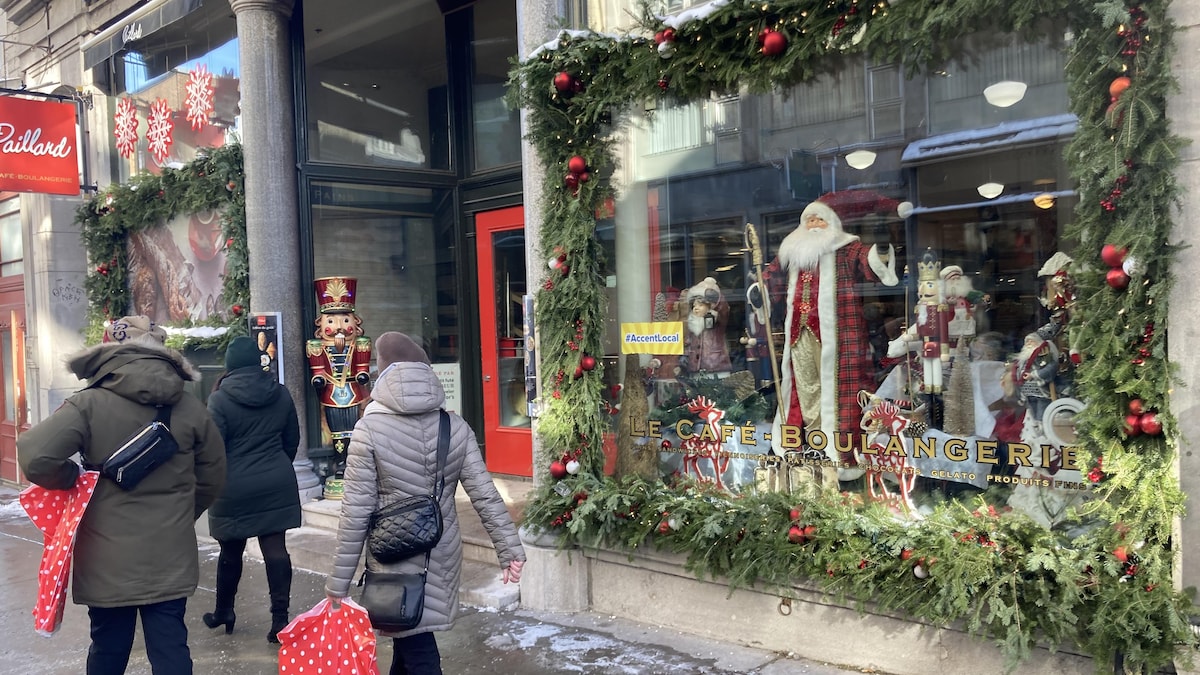 La vitrine d'un commerce décoré avec des branches de sapin, des guirlandes lumineuses et un père Noël.