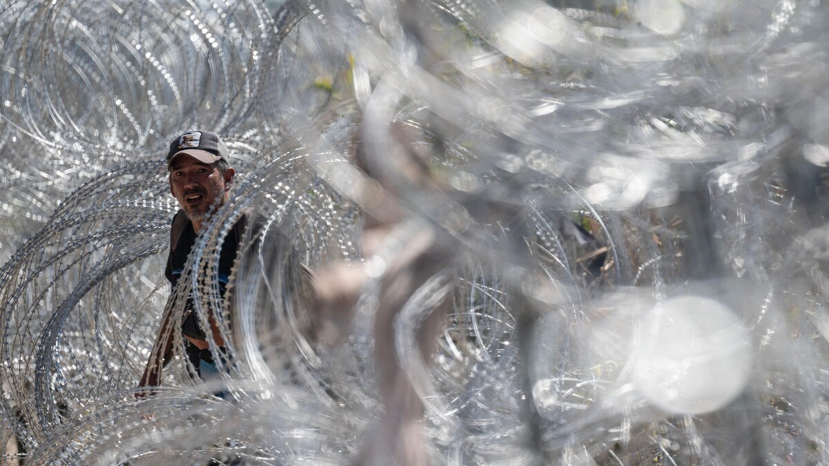 Un migrant traverse une barrière de barbelés. 