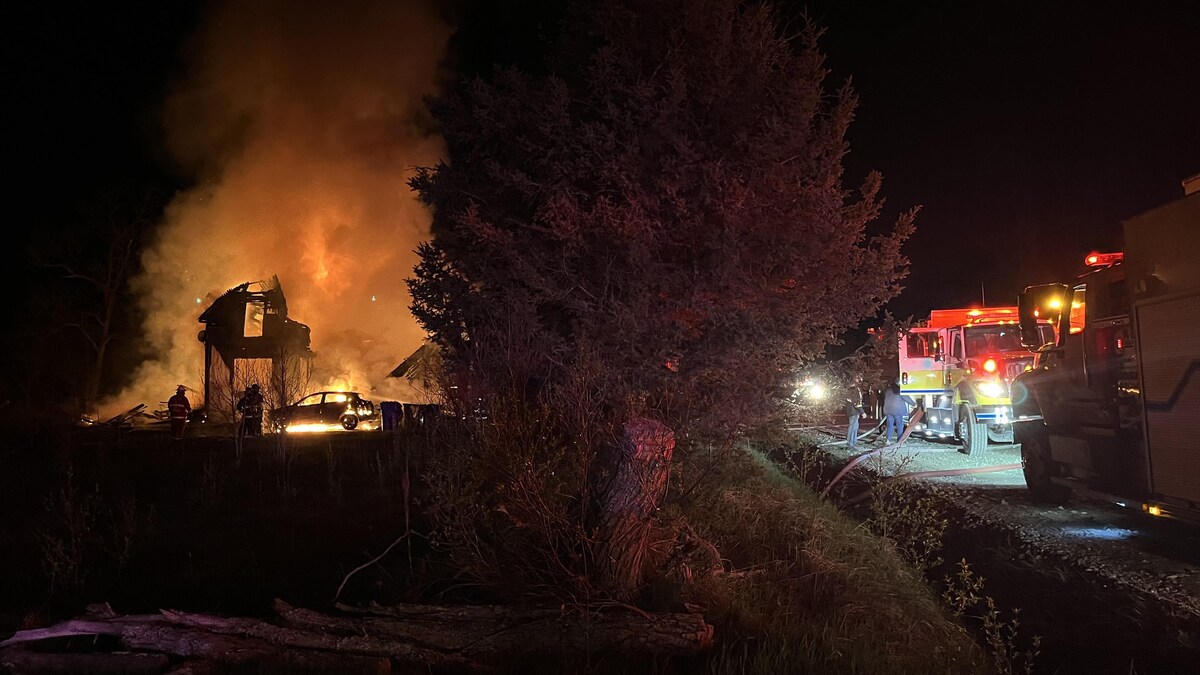 Un incendie dans une résidence et un véhicule, des camions de pompiers stationnés dans le chemin.