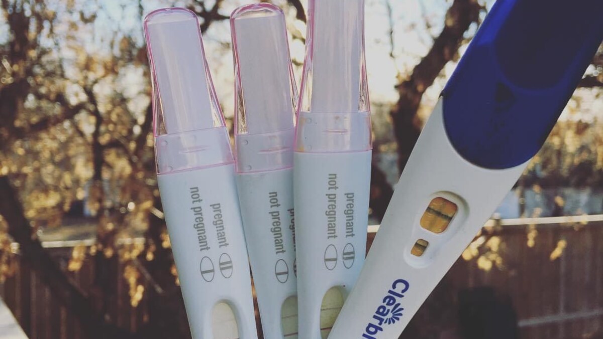 Quatre tests de grossesse négatifs tenus dans une main.