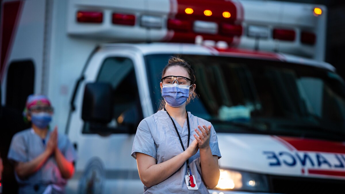 Deux femmes portant un masque devant une ambulance.